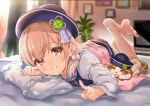  1girl amai_hiyo amai_hiyo_channel bed blurry blurry_background blush brown_eyes brown_hair cat clover_hair_ornament ekakibito four-leaf_clover_hair_ornament hair_ornament hat highres legs_up looking_at_viewer lying official_art on_stomach picture_frame pillow short_hair solo television virtual_youtuber 