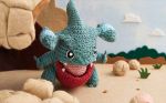  amigurumi_(medium) asako_ito commentary creature english_commentary full_body gen_4_pokemon gible multiple_sources no_humans official_art photo pokemon pokemon_(creature) pokemon_trading_card_game solo third-party_source 