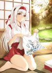  1girl bangs bare_legs barefoot blush breasts brown_eyes eyebrows_visible_through_hair folded_clothes grass hairband hakama_skirt headband highres indoors japanese_clothes kantai_collection kuromayu large_breasts leaf_print long_hair long_sleeves looking_at_viewer red_headband rock shoukaku_(kantai_collection) sitting sliding_doors smile solo tasuki tatami tree wariza white_hair wooden_floor 