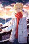  1girl ahoge artoria_pendragon_(all) bangs blonde_hair blue_eyes blue_ribbon braid braided_bun breath clouds coat commentary cowboy_shot elker evening eyebrows_visible_through_hair fate/stay_night fate_(series) green_eyes hair_between_eyes hair_ribbon highres lighthouse long_sleeves looking_at_viewer multicolored multicolored_eyes ocean outdoors railing red_scarf ribbon saber scarf short_hair sidelocks sleeves_past_wrists smile snow snowing standing sunset white_coat winter winter_clothes 