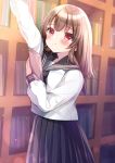  1girl :3 arm_up bangs black_sailor_collar black_skirt blurry blurry_background blush book bookshelf brown_hair closed_mouth commentary_request depth_of_field eyebrows_visible_through_hair hair_between_eyes highres holding holding_book indoors library long_hair looking_at_viewer minami_saki original pleated_skirt reaching red_eyes sailor_collar school_uniform serafuku shirt skirt solo standing white_shirt 