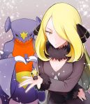  1girl black_coat black_pants blonde_hair character_doll closed_mouth coat commentary_request cynthia_(pokemon) doll fur-trimmed_coat fur_collar fur_trim garchomp gen_4_pokemon grey_eyes hair_ornament hair_over_one_eye hand_up holding holding_doll kurochiroko long_hair long_sleeves looking_down pants poke_ball poke_ball_(basic) pokemon pokemon_(creature) pokemon_(game) pokemon_dppt shiny shiny_hair smile sparkle spread_fingers 