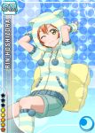  1girl animal_ears blue_background blush cat_ears character_name green_eyes hoodie hoshizora_rin love_live!_school_idol_project official_art orange_hair pillow short_hair shorts smile solo wink 