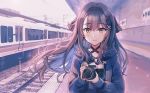  1girl black_hair blurry blurry_background blush brown_eyes camera ground_vehicle headband holding holding_camera hood hoodie long_hair long_sleeves looking_at_viewer original rangu sky solo standing train train_station 