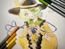  1girl art_tools_in_frame black_hat bow buttons character_name collared_shirt commentary diamond_button eyeball frilled_shirt_collar frilled_sleeves frills green_eyes green_hair hat hat_bow heart heart_of_string highres komeiji_koishi long_sleeves looking_at_viewer medium_hair neruko_(piano00324) open_mouth photo_(medium) shirt smile solo third_eye touhou traditional_media wide_sleeves yellow_bow yellow_shirt 