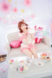  1girl birthday_cake brown_eyes brown_hair cake commentary_request cosplay cosplay_photo couch dessert food grin happiness_roomwear_(idolmaster) happy_birthday highres holding holding_cake holding_food idolmaster idolmaster_million_live! idolmaster_million_live!_theater_days indoors kasuga_mirai kasuga_mirai_(cosplay) looking_at_viewer macaron medium_hair on_couch one_side_up pajamas photo_(medium) pillow real_life shirt short_hair short_sleeves sitting smile solo table voice_actor voice_actor_connection yamazaki_haruka 