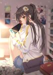  1girl ahoge barefoot black_hair blue_shorts blurry blurry_background book brown_eyes commentary depth_of_field flower from_behind hair_flower hair_ornament hairclip highres holding jacket knees_up long_hair long_sleeves looking_at_viewer looking_back nintendo_switch original picture_frame ponytail rosuuri short_shorts shorts sidelocks sitting solo thighs white_jacket 
