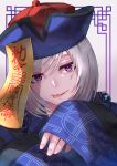  1boy aibon akudama_drive blue_headwear chinese_clothes cutthroat_(akudama_drive) hat highres jiangshi looking_at_viewer male_focus mole mole_under_eye ofuda qing_guanmao smile solo tongue tongue_out upper_body violet_eyes white_hair wide_sleeves 
