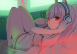  1girl absurdres adjusting_headphones ayanami_(azur_lane) ayanami_(niconico)_(azur_lane) azur_lane bangs bare_legs barefoot bed_sheet blurry collarbone commentary_request depth_of_field eyebrows_visible_through_hair eyes_visible_through_hair from_side headgear headphones highres long_hair looking_at_viewer looking_to_the_side lying monitor official_alternate_costume oversized_clothes oversized_shirt parted_lips ponytail red_eyes rindou_ringdong shirt sidelocks silver_hair solo t-shirt thighs 