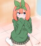  1girl bangs blue_eyes blush clothes_writing commentary_request covered_mouth eyebrows_behind_hair go-toubun_no_hanayome green_hoodie green_ribbon grey_skirt hair_between_eyes hair_ribbon highres hood hood_down hoodie kujou_karasuma long_sleeves looking_at_viewer nakano_yotsuba no_shoes plaid plaid_skirt pleated_skirt ribbon signature sitting skirt sleeves_past_wrists socks soles solo wariza white_legwear 