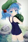 1girl alternate_costume ass bananannu blue_hair blue_swimsuit day flat_cap food from_behind fruit green_headwear grey_background hair_bobbles hair_ornament hat highres holding holding_food kawashiro_nitori looking_at_viewer looking_back one-piece_swimsuit outdoors rock school_swimsuit short_hair solo stream swimsuit touhou two_side_up wading watermelon