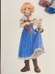  1girl alice_margatroid art_tools_in_frame blonde_hair blue_dress book boots brown_boots capelet closed_mouth commentary_request doll dress frilled_dress frills full_body grimoire grimoire_of_alice hairband highres holding holding_book jewelry lace-up_boots looking_at_viewer photo_(medium) puppet_rings red_hairband red_sash ring sash shanghai_doll shiratama_(hockey) short_hair smile solo touhou traditional_media waist_sash white_capelet yellow_eyes 