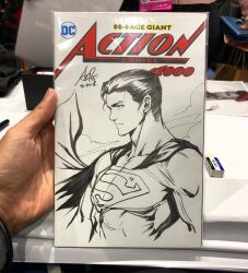  1boy art_tools_in_frame artist's_hand_in_frame cape clark_kent closed_mouth commentary cover_sketch dc_comics english_commentary from_side male_focus marker_(medium) monochrome muscular muscular_male photo_(medium) short_hair signature sketch solo stanley_lau superman superman_(series) superman_logo traditional_media upper_body 