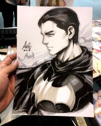  1boy art_tools_in_frame artist's_hand_in_frame bat_(animal) batman_(series) batman_symbol bruce_wayne cape closed_mouth commentary dc_comics english_commentary highres male_focus marker_(medium) monochrome photo_(medium) short_hair signature stanley_lau traditional_media upper_body 