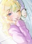  1girl bangs blonde_hair blue_eyes blurry blurry_foreground blush commentary_request depth_of_field eyebrows_visible_through_hair fujima_(k114) highres idolmaster idolmaster_cinderella_girls long_hair long_sleeves lower_teeth lying on_stomach one_eye_closed ootsuki_yui purple_sweater smile solo sweater upper_body 