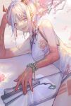  1girl absurdres arknights bangs bare_arms breasts china_dress chinese_clothes dragon_horns dress fan flower highres horns kotatsu_kaya long_hair looking_at_viewer lying nian_(arknights) nian_(unfettered_freedom)_(arknights) open_mouth plum_blossoms silver_hair smile solo violet_eyes 
