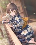  1girl absurdres animal animal_on_hand bangs barefoot blue_flower blue_kimono blurry blurry_background blush brown_hair closed_mouth commentary_request depth_of_field dutch_angle floral_print flower green_eyes hair_between_eyes hair_flower hair_ornament hairclip highres holding japanese_clothes kimono leaf leaves_in_wind long_hair nogi_momoko original outdoors print_kimono rabbit railing sash sitting smile solo x_hair_ornament 
