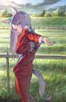  1girl animal_ears commentary_request day feet_out_of_frame fence from_side grass grin head_tilt highres horse_ears horse_tail long_hair looking_at_viewer mejiro_mcqueen_(umamusume) outdoors purple_hair red_track_suit sky smile solo standing stretch sun tail tentsuu_(tentwo) umamusume violet_eyes 