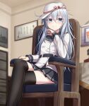  1girl armchair belt black_legwear black_skirt blue_eyes blurry blurry_background blush chair closed_mouth crossed_legs eyebrows_visible_through_hair flat_cap hair_between_eyes hammer_and_sickle hat hibiki_(kancolle) highres indoors kantai_collection long_hair long_sleeves looking_at_viewer pleated_skirt silver_hair sitting skirt smile solo thigh-highs verniy_(kancolle) white_headwear yakob_labo 