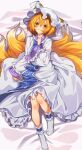  1girl animal_ears bangs blonde_hair blush breasts closed_mouth commentary_request dress eyes_visible_through_hair fox_ears fox_tail frills frown full_body hair_between_eyes hand_up hat head_tilt highres kitsune large_breasts long_sleeves looking_at_viewer lying manarou multiple_tails no_shoes on_back petticoat pillow_hat raised_eyebrows short_hair solo tabard tail tassel touhou white_dress white_headwear wide_sleeves yakumo_ran yellow_eyes 