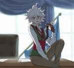  1boy bangs blurry blurry_background blush brown_neckwear brown_pants collarbone collared_shirt commentary dangan_ronpa_(series) dangan_ronpa_2:_goodbye_despair desk feet_out_of_frame green_vest grey_eyes hair_between_eyes hand_up knee_up komaeda_nagito long_sleeves looking_at_viewer male_focus official_alternate_costume open_mouth pants paper red_vest shirt sitting solo upper_teeth vest white_hair yandr4hope 