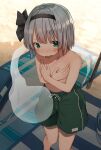  1girl absurdres beach beach_towel blush commentary_request covering covering_breasts crossdressinging flat_chest hairband highres konpaku_youmu looking_at_viewer male_swimwear male_swimwear_challenge mamemochi short_hair silver_hair solo sweatdrop swim_trunks topless touhou towel wavy_mouth 