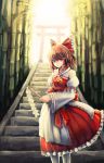  1girl adapted_costume bad_id bamboo bamboo_forest brown_hair bryanth detached_sleeves forest gohei hakurei_reimu highres looking_at_viewer nature red_eyes solo stairs standing sunlight torii touhou 