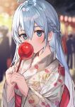  1girl ahoge aroa_(aroamoyasi) bangs blue_eyes blue_hair blurry blurry_background blush braid candy_apple commentary_request covering_mouth depth_of_field eyebrows_visible_through_hair festival floral_print food hair_between_eyes highres holding japanese_clothes kimono long_hair looking_at_viewer night original outdoors solo_focus upper_body 
