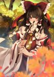  1girl ascot autumn_leaves blurry blurry_background blush bow brown_eyes brown_hair covering_mouth eyebrows_visible_through_hair frilled_shirt_collar frills gohei hair_between_eyes hair_bow hair_tubes hakurei_reimu highres long_hair looking_at_viewer meji_aniki nontraditional_miko red_bow red_skirt red_vest ribbon-trimmed_sleeves ribbon_trim skirt solo touhou vest wide_sleeves 