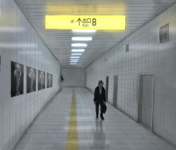  1boy black_hair black_jacket briefcase collared_shirt commentary_request cosmo_(465lilia) geeta_(pokemon) glimmet hallway highres holding holding_briefcase jacket larry_(pokemon) long_sleeves male_focus necktie pokemon pokemon_(creature) pokemon_sv poster_(object) salaryman shadow shirt the_exit_8 tile_floor tile_wall tiles white_necktie 