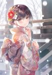  1girl bangs blush brown_hair building floral_print flower furisode hair_flower hair_ornament highres japanese_clothes kimono long_hair long_sleeves looking_at_viewer looking_back miwabe_sakura obi original parted_lips pink_eyes pink_kimono sash smile snow snowing solo standing tied_hair tree 