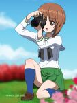  1girl artist_name bangs blue_legwear blue_sky blurry blurry_background blurry_foreground camera clouds cloudy_sky commentary_request dated depth_of_field eyebrows_visible_through_hair girls_und_panzer grass highres holding holding_camera looking_to_the_side naotosi nishizumi_miho one_knee open_mouth outdoors short_hair single-lens_reflex_camera sky smile solo taking_picture 