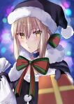  1girl artoria_pendragon_(all) ass bangs black_legwear blonde_hair blue_cloak blue_dress blue_gloves blue_headwear blurry blurry_background breasts brown_eyes christmas christmas_lights christmas_tree cloak commentary_request depth_of_field dress dutch_angle eyebrows_visible_through_hair fate/grand_order fate/stay_night fate_(series) fur-trimmed_cloak fur-trimmed_hood fur_trim gloves hair_between_eyes hat highres holding holding_sack hood hood_down hooded_cloak medium_breasts pantyhose saber_alter sack santa_costume santa_hat sii_artatm solo 