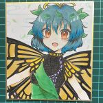 1girl antennae aqua_hair butterfly_wings dress eternity_larva eyebrows_visible_through_hair fairy green_dress hair_between_eyes highres leaf leaf_on_head multicolored_clothes multicolored_dress open_mouth orange_eyes photo_(medium) shikishi short_hair short_sleeves single_strap smile solo touhou upper_body wings yami_nabe 