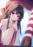  1girl :d absurdres alternate_neckwear bare_shoulders blurry bow bowtie brown_hair day depth_of_field detached_sleeves dutch_angle eyebrows_behind_hair hair_bow hair_tubes hakurei_reimu highres kogalashi long_hair outdoors own_hands_together red_eyes smile solo touhou wide_sleeves yellow_bow yellow_bowtie 