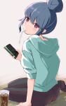  1girl ass blue_hair blush cellphone drink drinking_straw file112056 green_hoodie highres holding holding_phone hood hoodie looking_at_viewer looking_back on_floor phone shima_rin simple_background sitting smartphone sweater violet_eyes yurucamp 