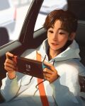  1boy asian brown_eyes brown_hair car_interior drawstring english_commentary got7 hair_behind_ear handheld_game_console highres holding holding_handheld_game_console hood hoodie k-pop male_focus mark_tuan nintendo_switch parted_lips real_life sam_yang sitting smile solo vehicle_interior white_hoodie 