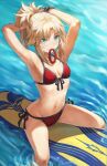  1girl armpits arms_behind_head arms_up bangs bare_shoulders bikini blonde_hair bracelet braid breasts collarbone fate/grand_order fate_(series) french_braid green_eyes highres jewelry long_hair looking_at_viewer mordred_(fate) mordred_(swimsuit_rider)_(fate) mordred_(swimsuit_rider)_(first_ascension)_(fate) mouth_hold navel ocean parted_bangs ponytail prydwen_(fate) red_bikini sidelocks small_breasts smile solo surfboard swimsuit thighs tonee tying_hair wet 