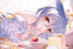  1girl animal_ears bare_shoulders blue_hair cake cat_ears finger_to_mouth fingernails food fork fruit grey_hair happy_birthday highres holding holding_fork long_sleeves looking_at_viewer lying on_stomach original pillow shirt strawberry suaynnai_wanzi white_shirt yellow_eyes 