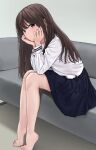  1girl akipeko bare_legs barefoot black_hair blue_skirt blush brown_eyes brown_hair couch feet head_rest heel_up highres long_hair long_sleeves looking_at_viewer on_couch original pleated_skirt school_uniform serafuku serious shirt sitting skirt solo straight_hair white_shirt 