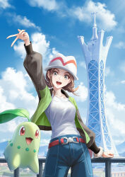  1girl :d arm_up belt blue_pants bracelet brown_hair chikorita collarbone commentary fence green_jacket happy harmony_(pokemon) hat highres jacket jewelry lumiose_city open_clothes open_jacket open_mouth pants pokemon pokemon_(creature) pokemon_legends:_z-a redpoke shirt smile teeth tower upper_teeth_only w white_hat white_shirt 