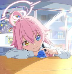  1girl ahoge blue_archive blue_eyes blush closed_mouth commentary_request crossed_bangs hair_between_eyes halo heterochromia highres hoshino_(blue_archive) long_hair long_sleeves nana01_art pink_hair pink_halo shirt smile stuffed_whale table white_shirt yellow_eyes 