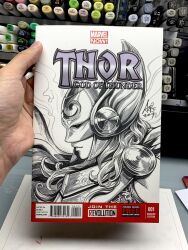  1girl armor art_tools_in_frame artist's_hand_in_frame closed_mouth comic_cover commentary cover cover_page cover_sketch english_commentary from_side helmet highres jane_foster long_hair marker_(medium) marvel monochrome photo_(medium) signature stanley_lau thor_(jane_foster) traditional_media winged_headwear 
