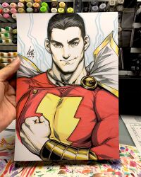  1boy art_tools_in_frame artist's_hand_in_frame black_hair bodysuit clenched_hand commentary dc_comics english_commentary gauntlets gold_gauntlets highres looking_at_viewer male_focus marker_(medium) photo_(medium) red_bodysuit shazam short_hair signature smile solo stanley_lau traditional_media upper_body 