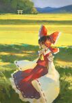  1girl ascot bangs blush bow brown_eyes brown_hair closed_mouth collared_vest commentary detached_sleeves feet_out_of_frame field fjsmu frilled_bow frills grass hair_bow hair_tubes hakurei_reimu highres looking_at_viewer medium_hair mountainous_horizon nature red_bow red_skirt red_vest ribbon-trimmed_skirt ribbon-trimmed_sleeves ribbon_trim scenery skirt skirt_set sleeves_past_fingers sleeves_past_wrists solo torii touhou tree vest white_sleeves wide_sleeves wind yellow_ascot 