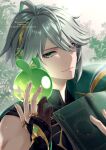 1boy alhaitham_(genshin_impact) antenna_hair bangs bare_shoulders black_gloves blurry blurry_background bodysuit book cape closed_mouth genshin_impact gloves green_cape green_eyes grey_hair hair_over_one_eye hand_up headphones holding holding_book leaf light_smile looking_at_viewer male_focus open_book partially_fingerless_gloves seelie_(genshin_impact) shoulder_cape solo twitter_username upper_body yamaya_aya 