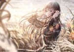  1girl bangs black_shirt blurry blurry_background blush brown_eyes brown_hair closed_mouth clouds grass hands_in_hair hands_up highres lace long_hair long_sleeves original outdoors sakura_(39ra) shirt sky solo standing sunset 
