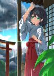  1girl absurdres arm_up bangs blue_sky closed_mouth clouds cloudy_sky commentary_request day green_eyes hair_between_eyes hair_ornament hair_tie hair_tie_in_mouth hairclip hakama hakama_skirt highres japanese_clothes kimono long_sleeves miko mouth_hold original outdoors rain red_hakama skirt sky solo torii tsuyukina_fuzuki water_drop white_kimono wide_sleeves x_hair_ornament 