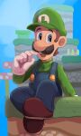  1boy blue_eyes blue_overalls boots brown_hair facial_hair gloves grass green_headwear green_shirt hat highres hiyashimeso luigi mustache on_grass open_mouth overalls platform shirt short_hair sitting super_mario_bros. teeth upper_teeth_only white_gloves 