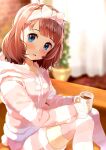  1girl :d blue_eyes blush bow brown_hair commentary couch cup curtains dot_nose feet_out_of_frame hair_bow hairband highres holding holding_cup hood hoodie hot_chocolate idolmaster idolmaster_million_live! indoors looking_at_viewer nira_(vira) plant potted_plant short_hair sitting smile suou_momoko thigh-highs 